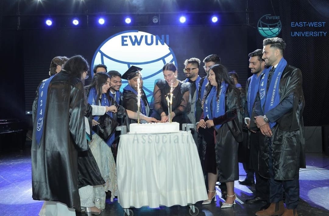 Indian graduates of East West University Georgia cutting a cake on their graduation night.